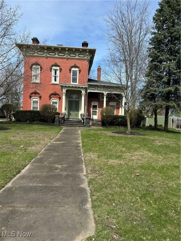 Italianate-style house with a chimney and a front lawn