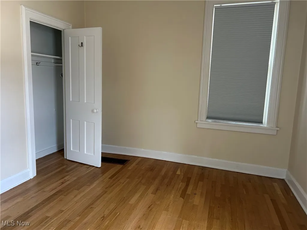 Unfurnished bedroom with wood finished floors and a closet