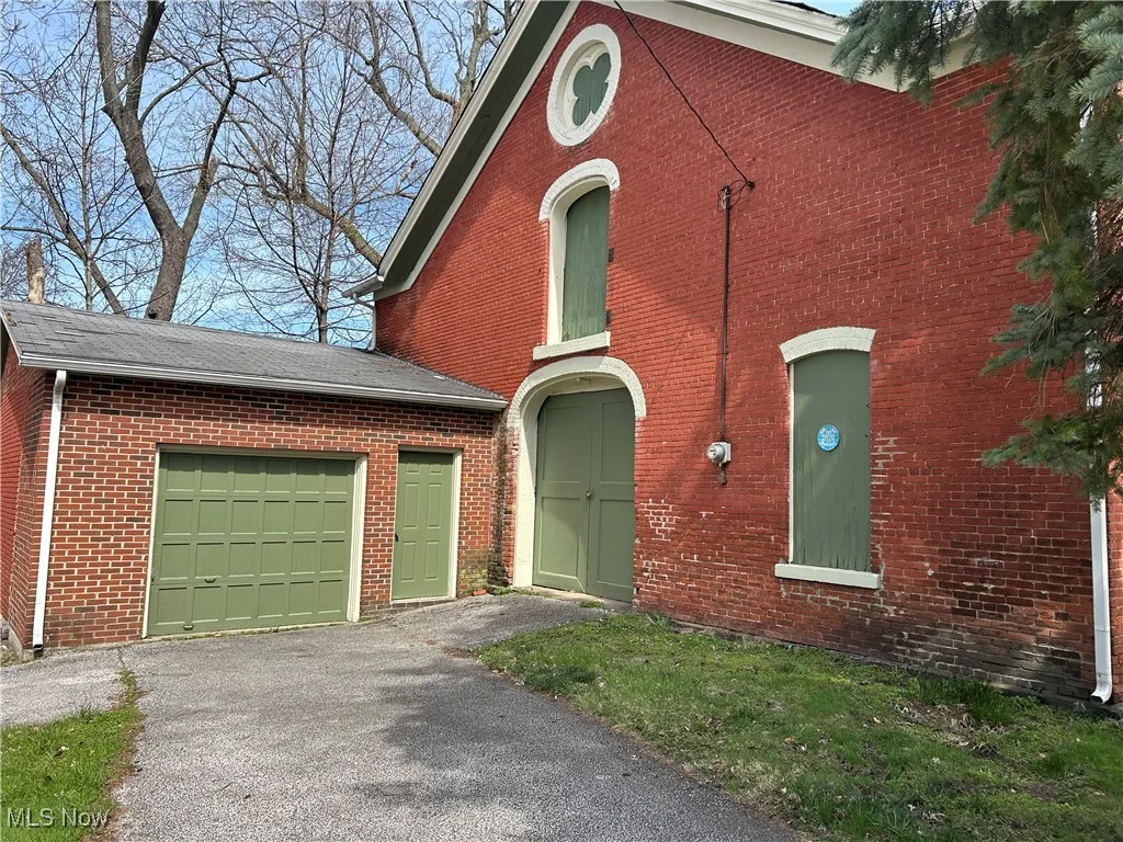 View of front of home featuring brick siding, asphalt driveway, and a shingled roof