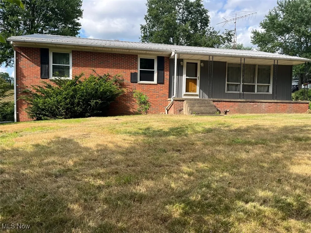 Ranch-style house with brick siding, a metal roof, and a front yard