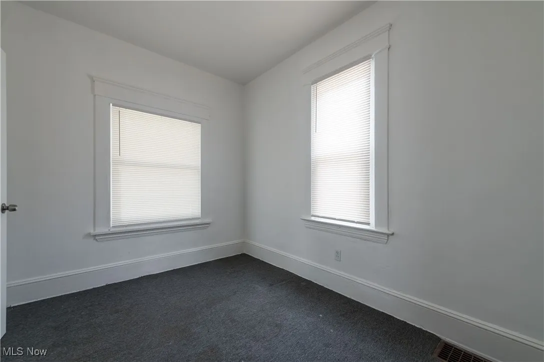 Empty room with dark colored carpet and baseboards