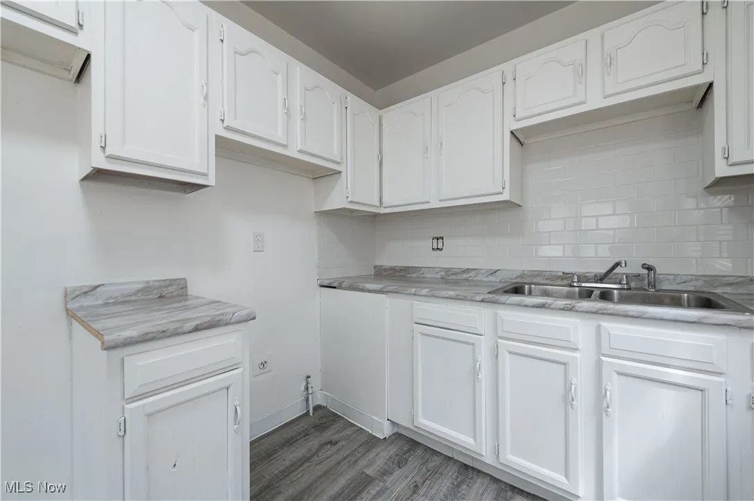 Kitchen featuring backsplash, white cabinetry, wood finished floors, and light countertops