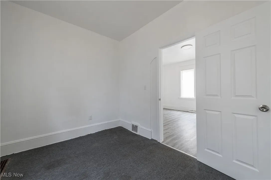 Spare room with baseboards and dark colored carpet