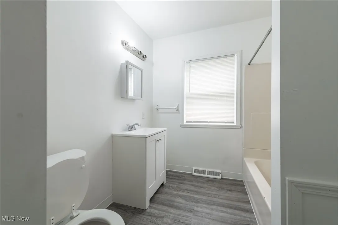 Bathroom with vanity, wood finished floors, and washtub / shower combination
