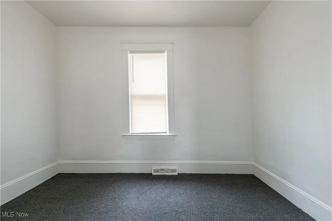 Empty room featuring dark carpet and baseboards