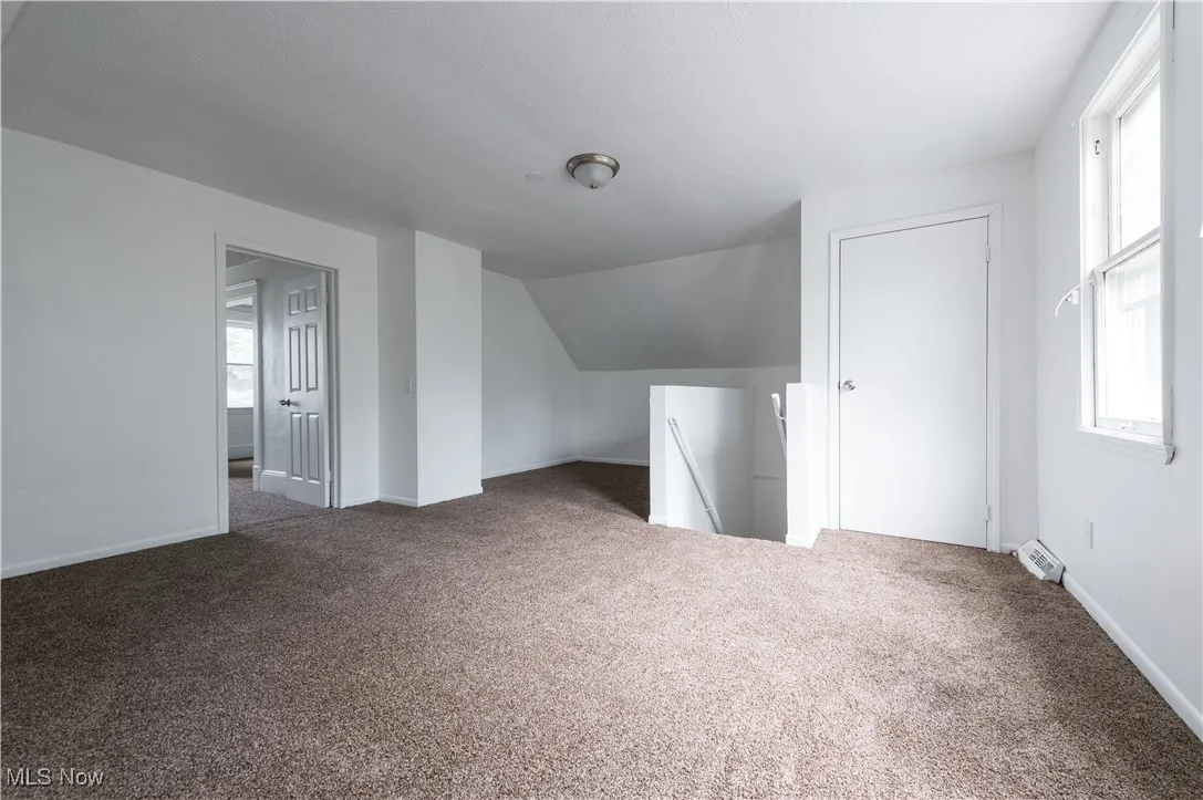 Additional living space with carpet flooring and lofted ceiling