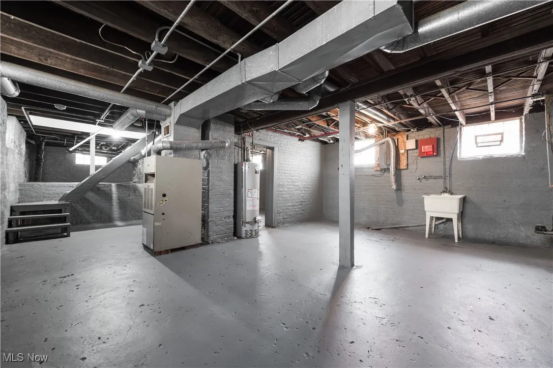 Basement featuring gas water heater, heating unit, and stairway