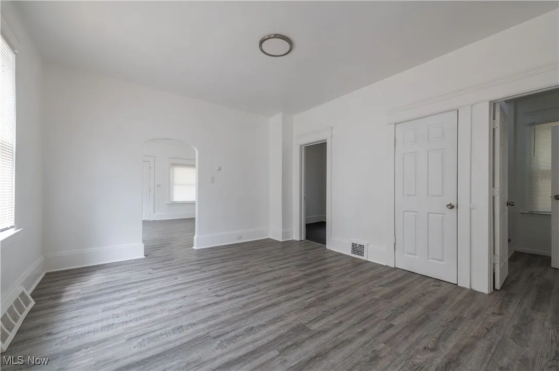 Unfurnished bedroom featuring arched walkways and wood finished floors