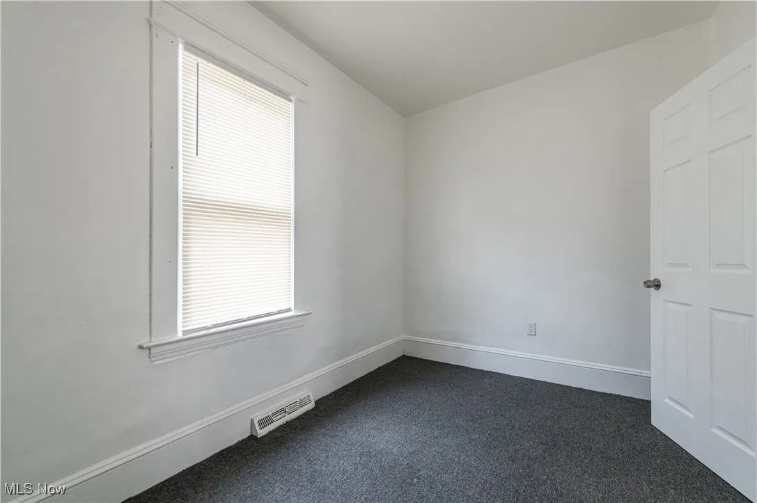 Unfurnished room with dark carpet and baseboards