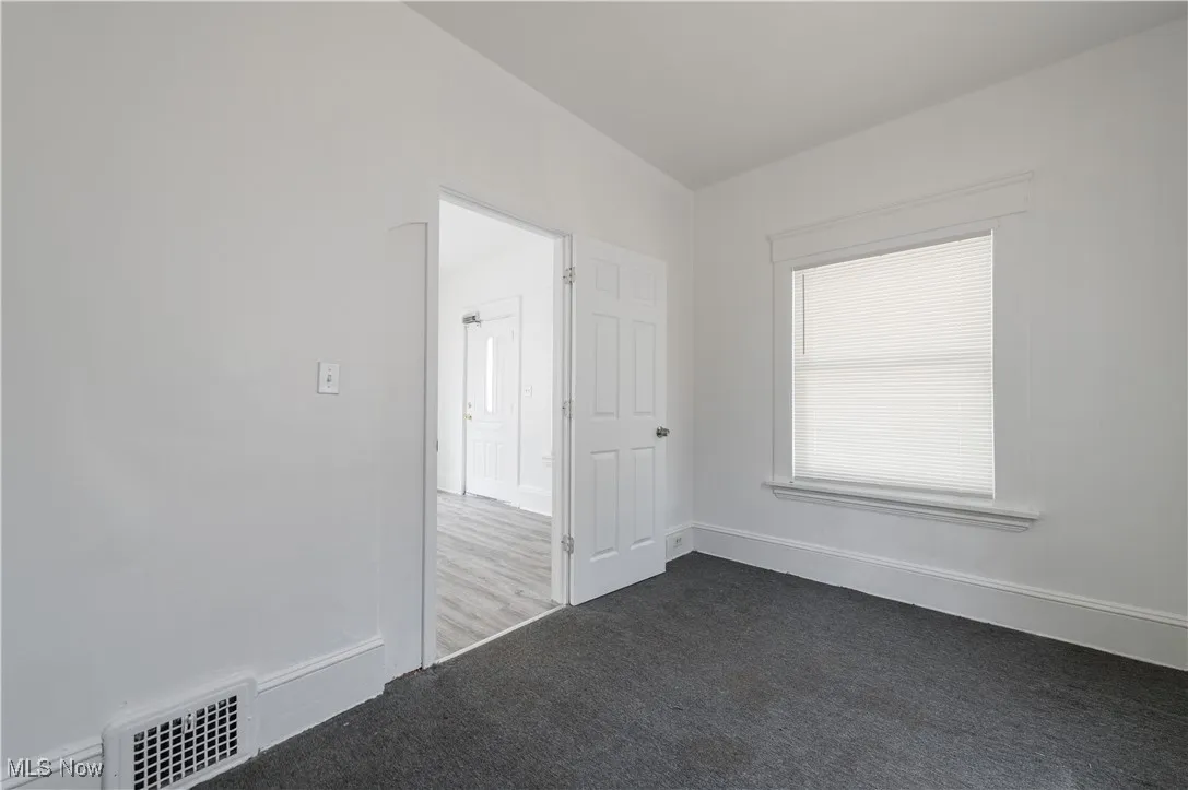 Unfurnished room featuring dark colored carpet and baseboards