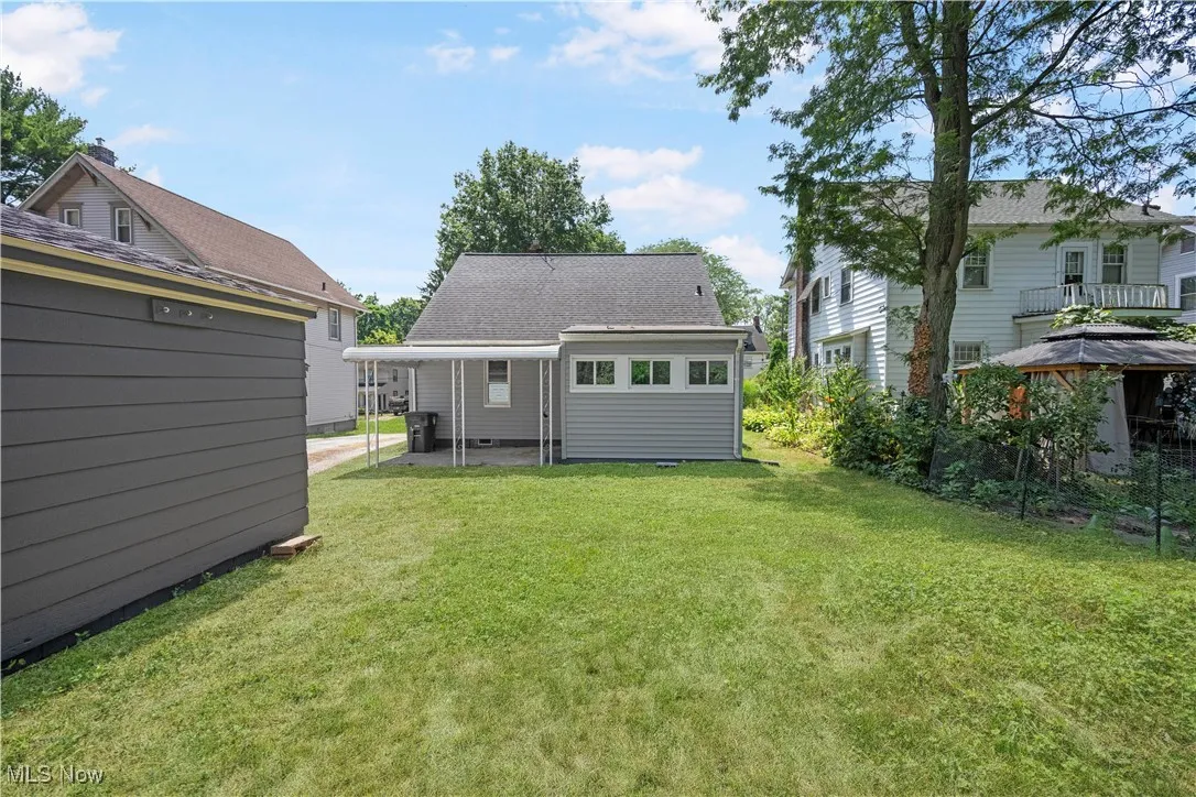 Back of house featuring a yard, an outdoor structure, and a shingled roof