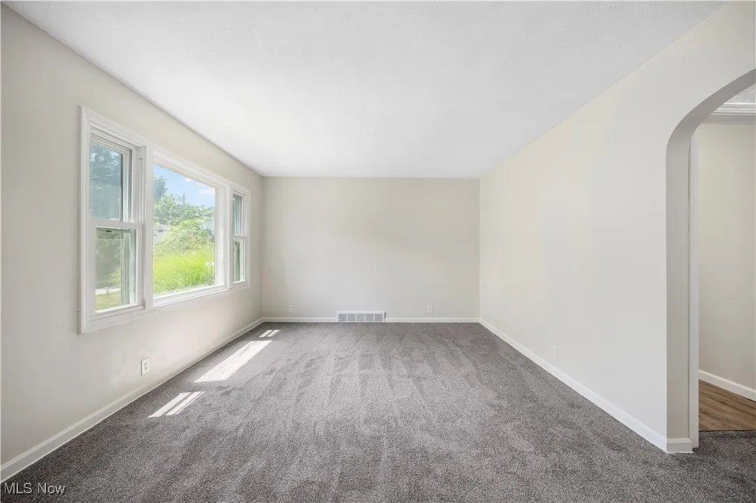 Empty room with arched walkways and carpet flooring