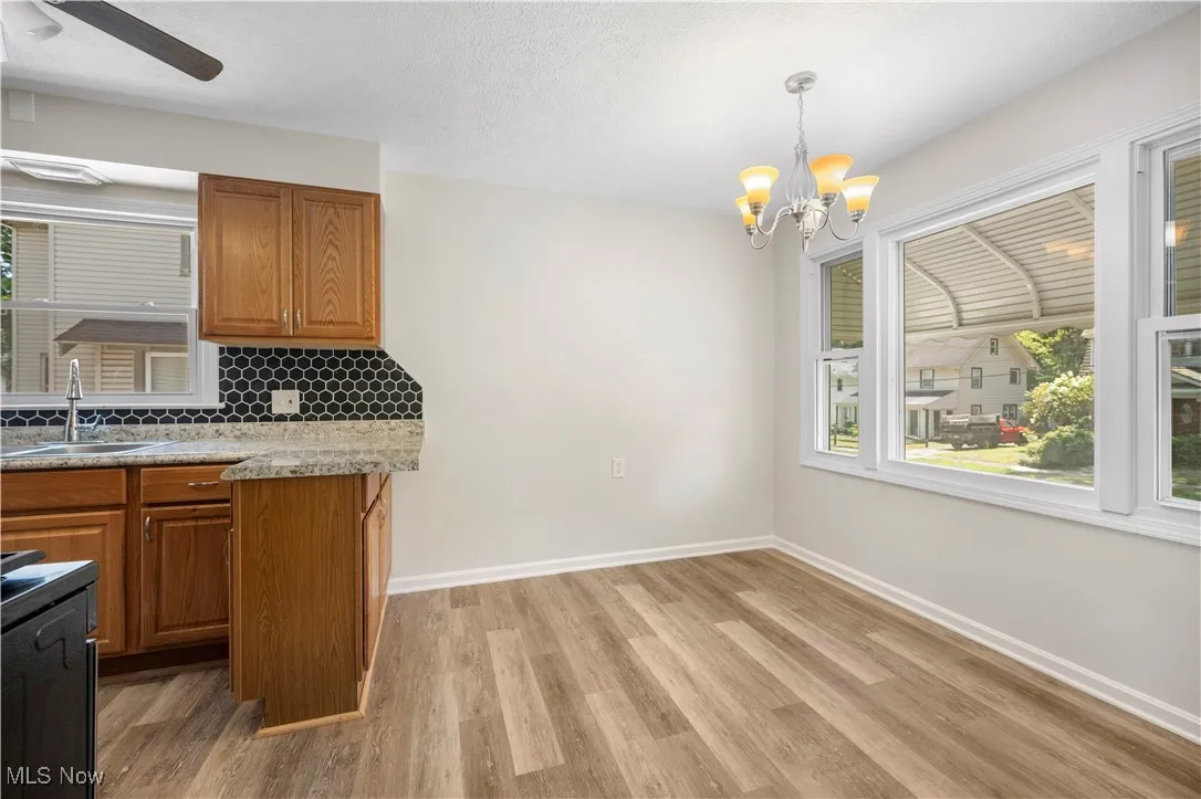 Kitchen with brown cabinets, a chandelier, a ceiling fan, backsplash, and a textured ceiling
