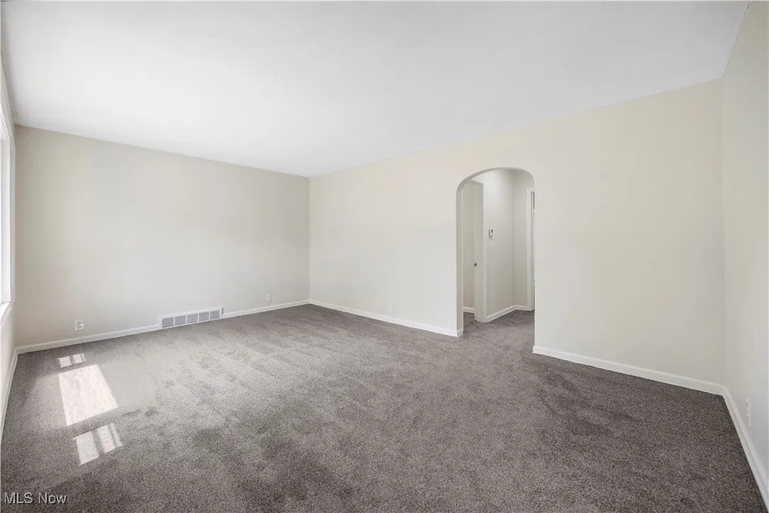Spare room featuring arched walkways and carpet
