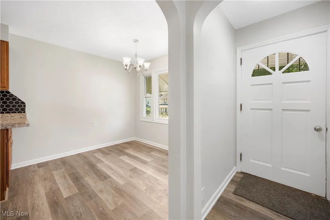 Foyer entrance featuring light wood finished floors, a chandelier, and arched walkways