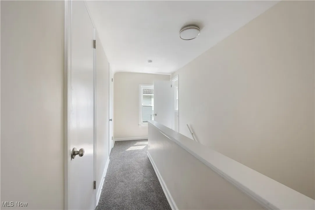 Hallway featuring dark carpet and an upstairs landing