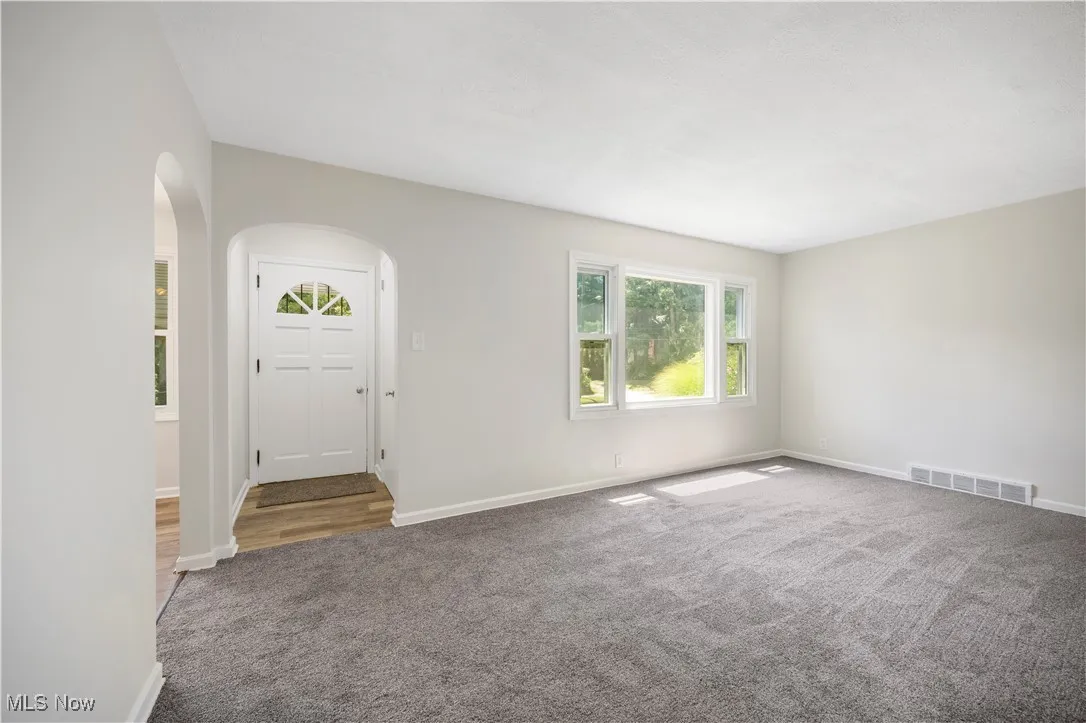 Carpeted foyer with arched walkways and baseboards
