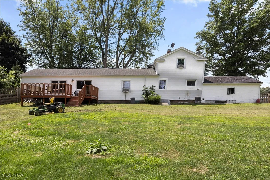 Rear view of property with a wooden deck, a yard, and roof with shingles