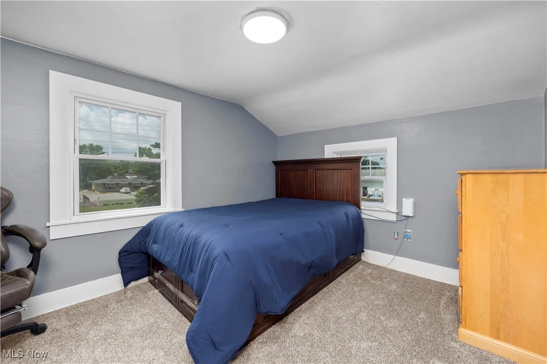 Bedroom with lofted ceiling, multiple windows, and carpet