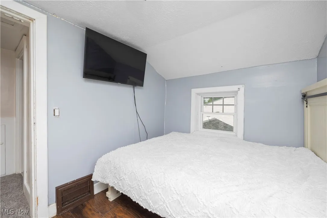 Bedroom featuring a textured ceiling, lofted ceiling, and wood finished floors