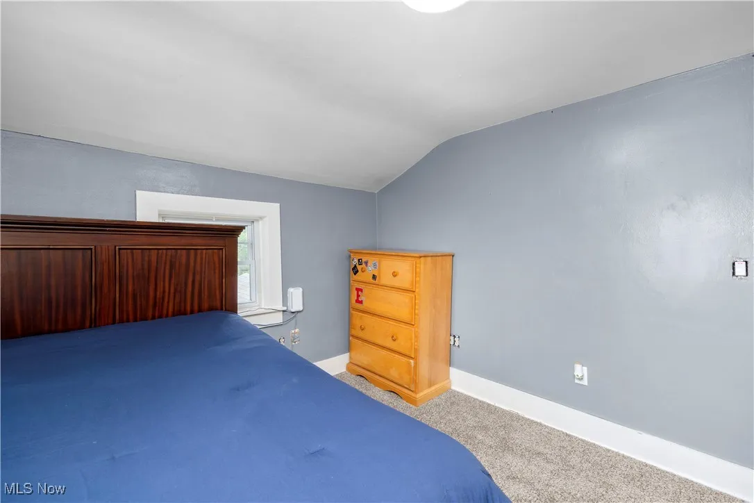 Bedroom featuring carpet and vaulted ceiling