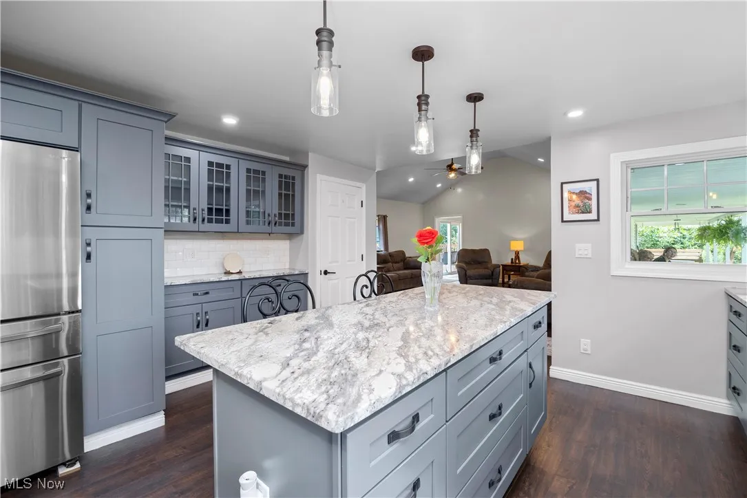 Kitchen featuring stainless steel refrigerator, vaulted ceiling, gray cabinetry, backsplash, and recessed lighting