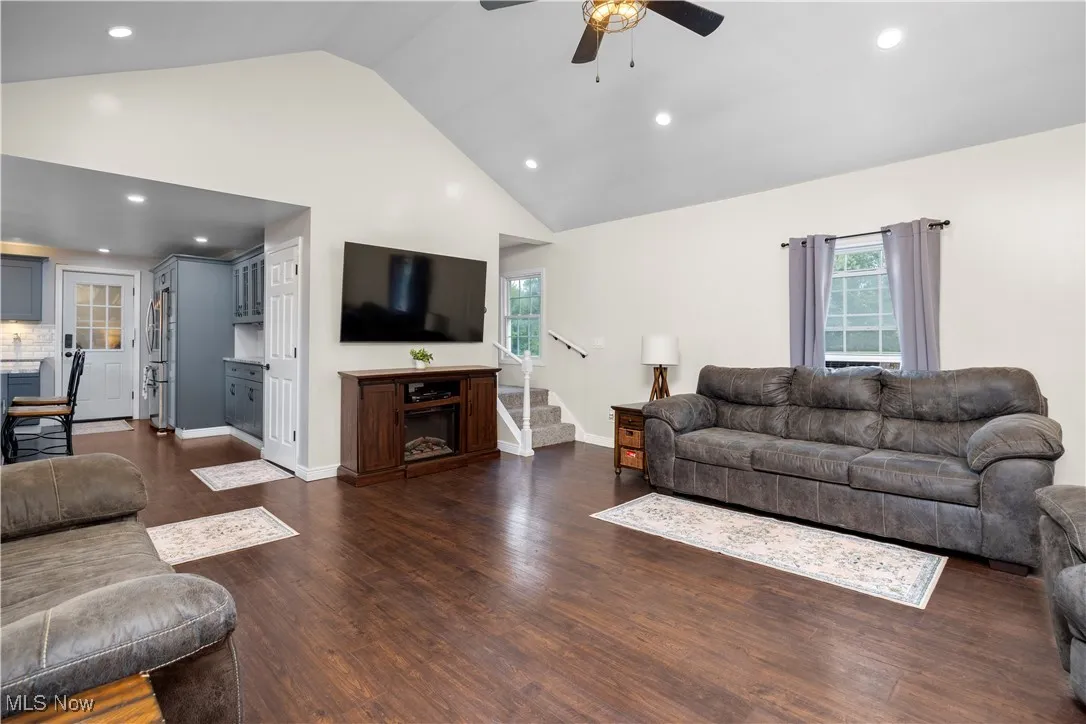 Living room with recessed lighting, healthy amount of natural light, stairs, ceiling fan, and dark wood-style floors