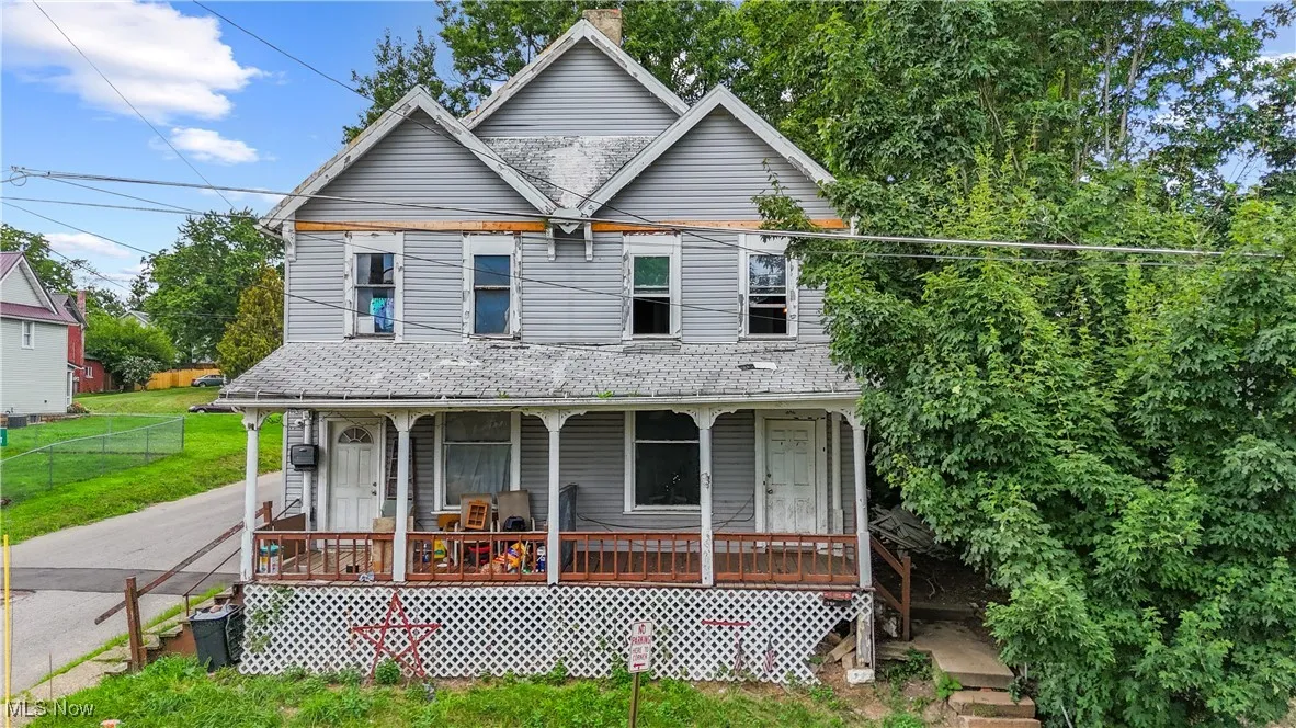 View of front of home featuring a porch, a shingled roof, and a chimney