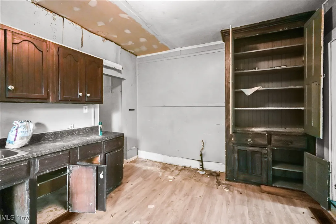Kitchen with light wood finished floors, dark countertops, and dark brown cabinets
