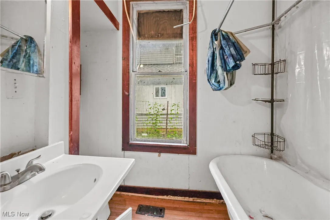 Full bath with a soaking tub and wood finished floors