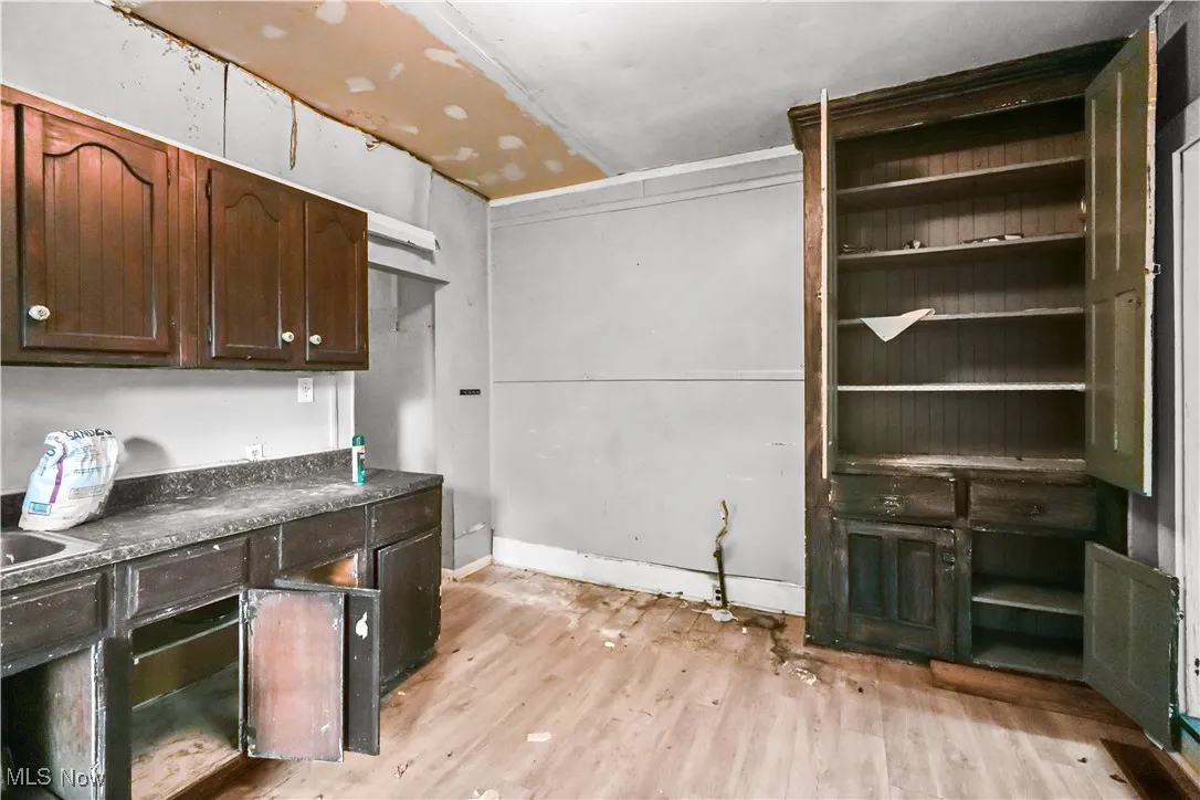 Kitchen featuring dark brown cabinets, dark countertops, and light wood finished floors
