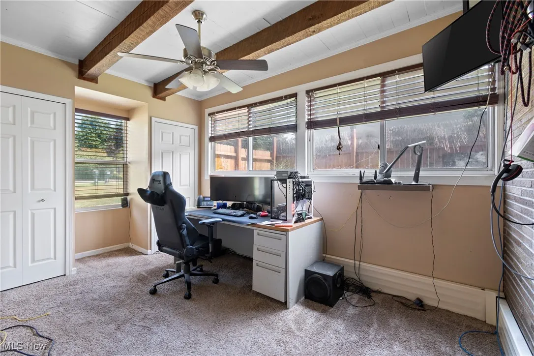 Carpeted home office with beam ceiling, a ceiling fan, and ornamental molding