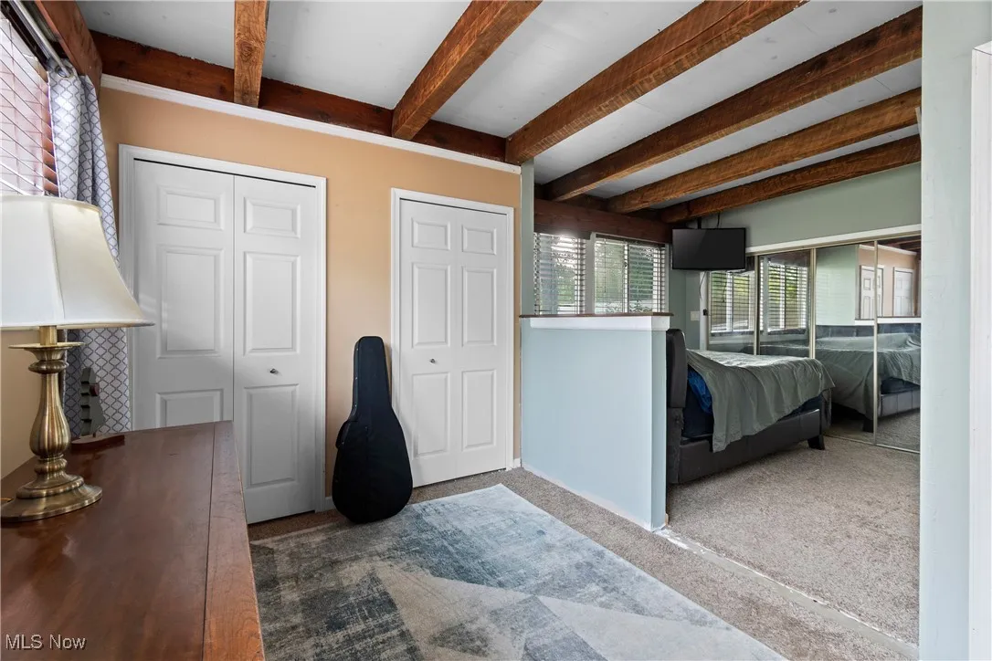 Carpeted bedroom with beamed ceiling and two closets