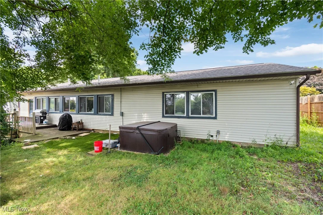 Back of property featuring a hot tub and a deck