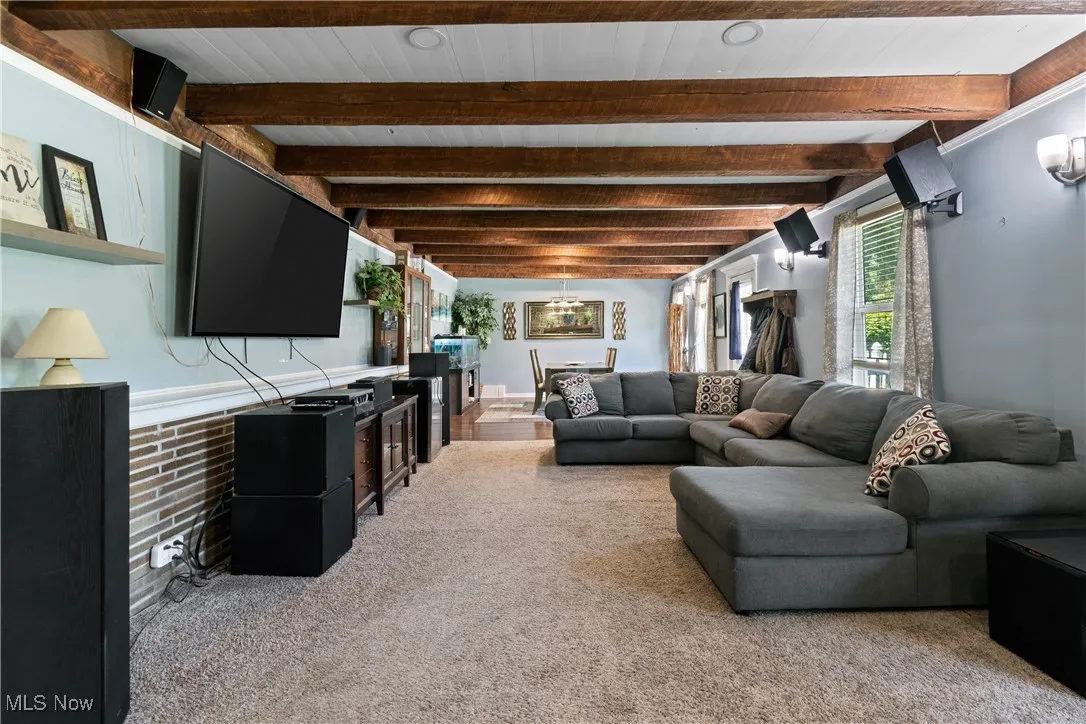 Living room featuring light colored carpet and beamed ceiling