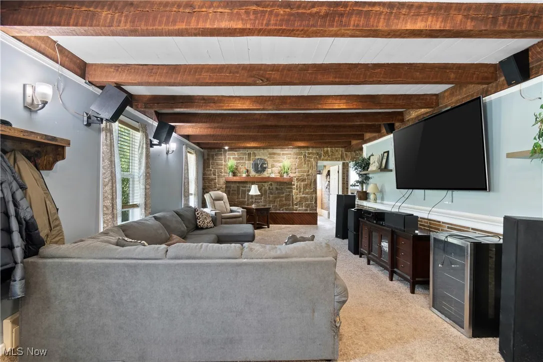 Living room featuring light colored carpet and beamed ceiling