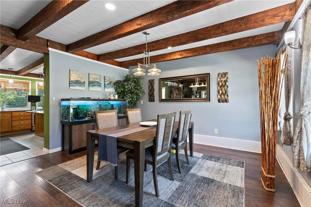 Dining area with healthy amount of natural light, wood finished floors, and beamed ceiling