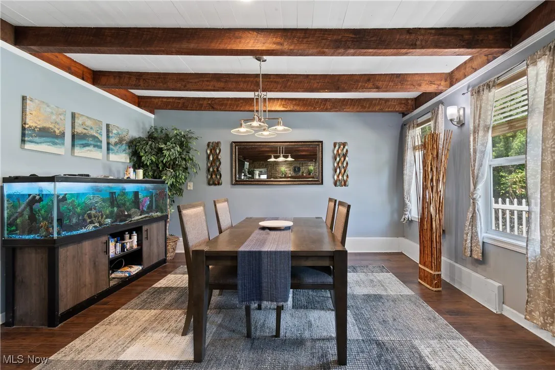Dining space with wood finished floors, a chandelier, and beam ceiling