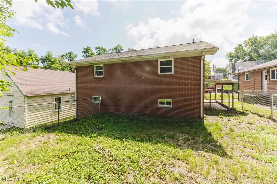 Back of house with a fenced backyard and brick siding
