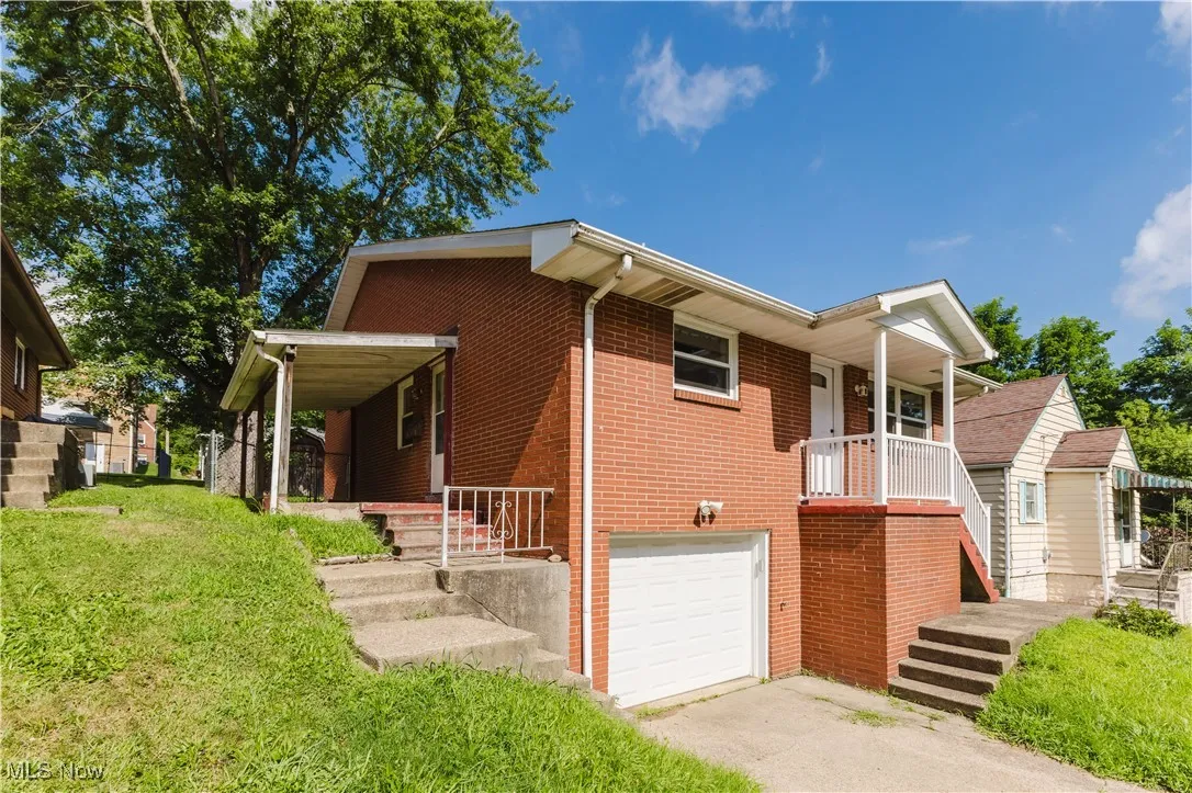 View of front of home with an attached garage, brick siding, driveway, and a front yard