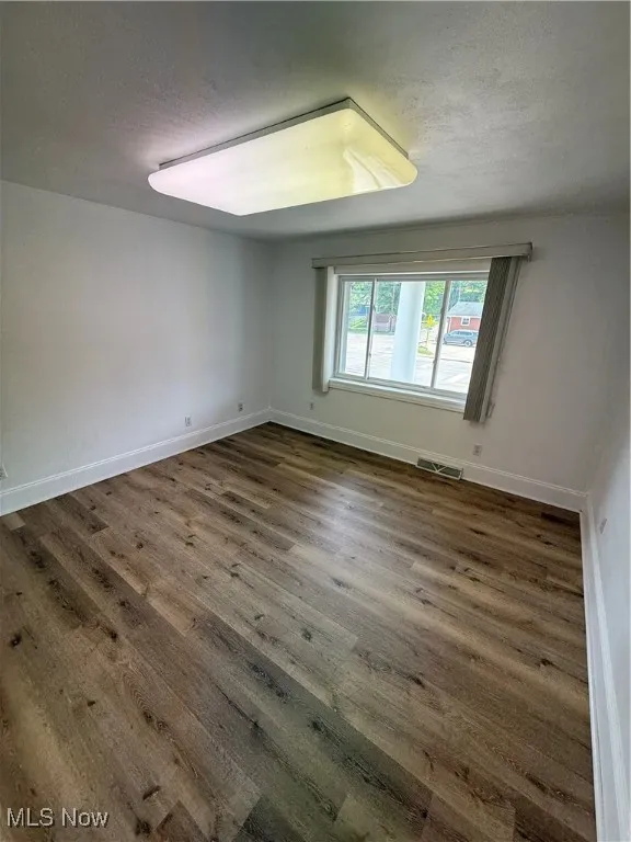 Unfurnished room featuring a textured ceiling and wood finished floors