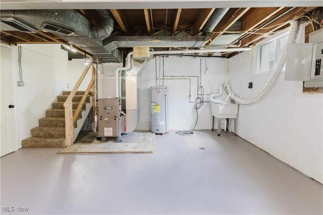 Basement featuring stairs, water heater, and heating unit