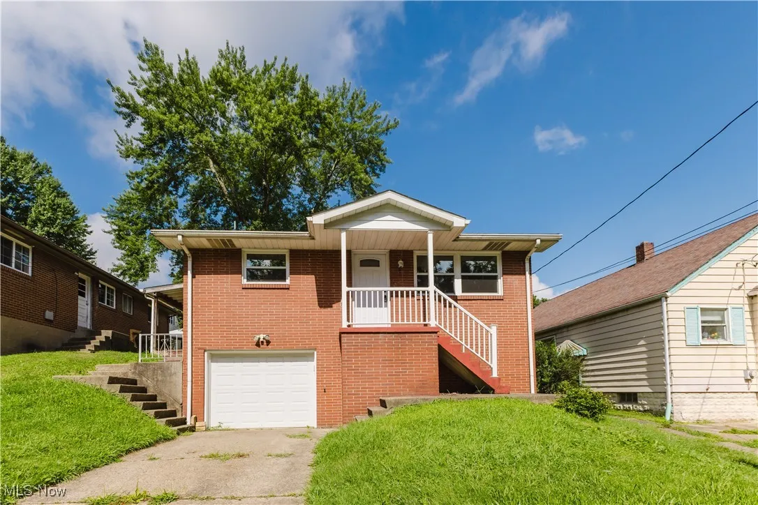 Ranch-style home with stairs, a garage, a front lawn, and driveway