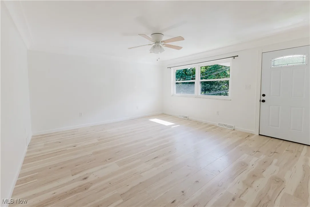 Entrance foyer with light wood finished floors, a ceiling fan, and ornamental molding