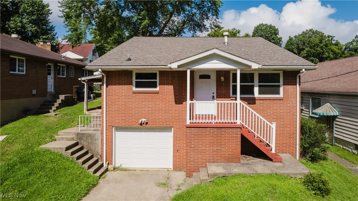 View of front of property featuring stairway, an attached garage, a shingled roof, driveway, and a front yard