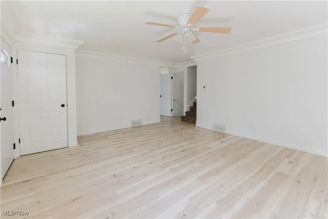 Spare room with ornamental molding, ceiling fan, stairway, and wood finished floors