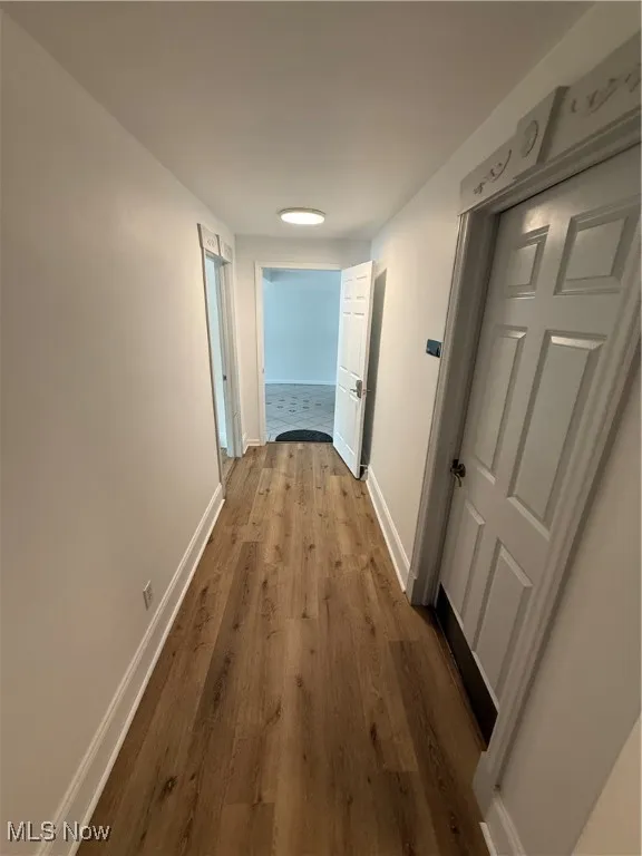 Hallway with dark wood-style flooring and baseboards