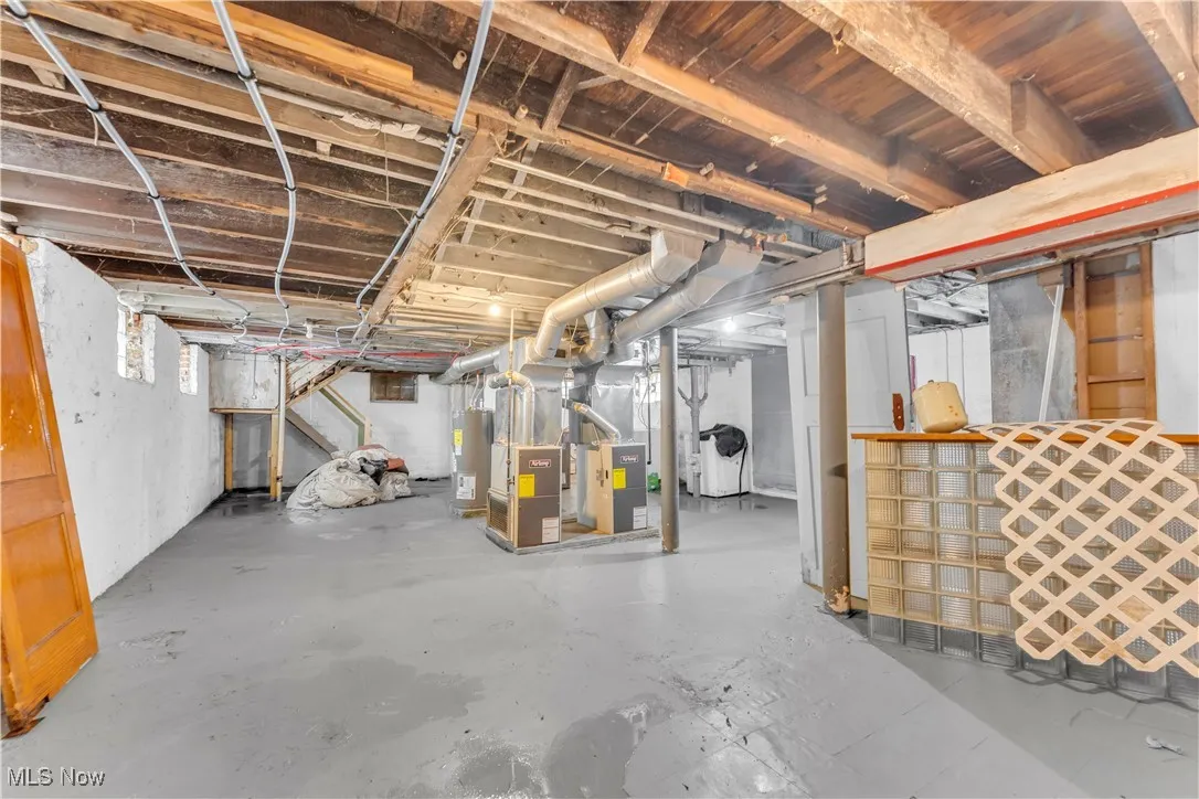 Below grade area featuring stairway, electric water heater, and heating unit