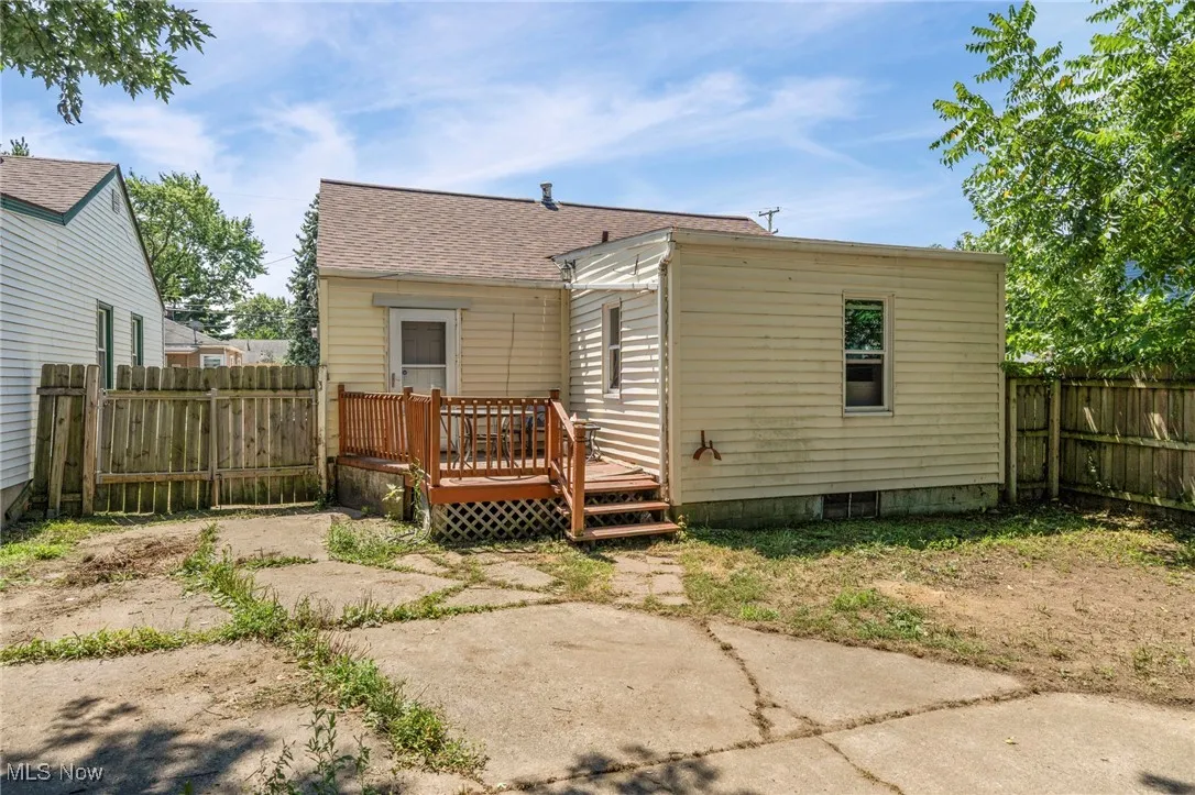 Back of house with a fenced backyard, a deck, and roof with shingles