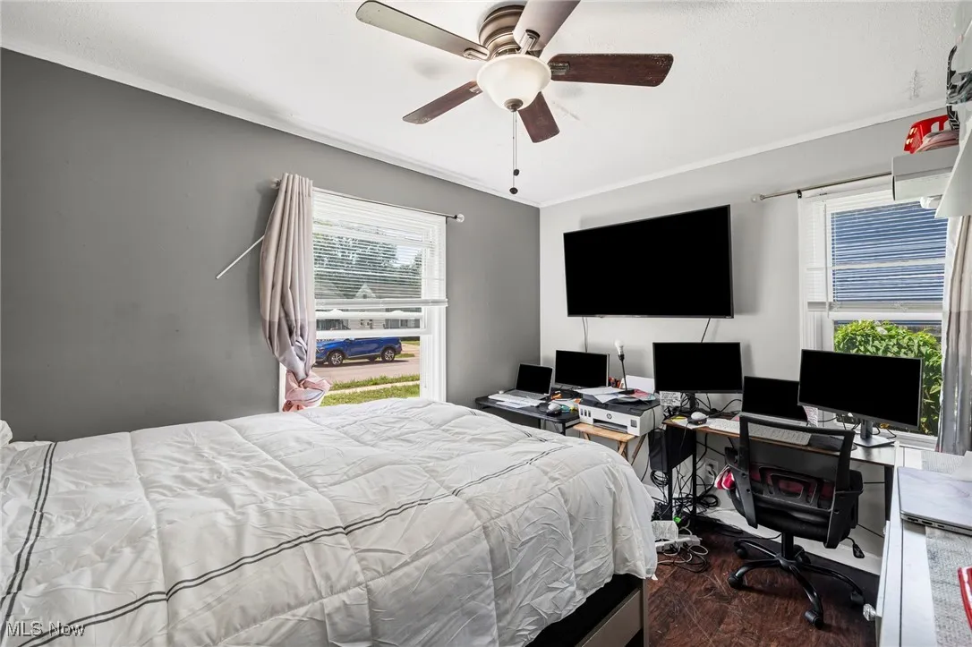 Bedroom with crown molding, wood finished floors, an office area, and a ceiling fan